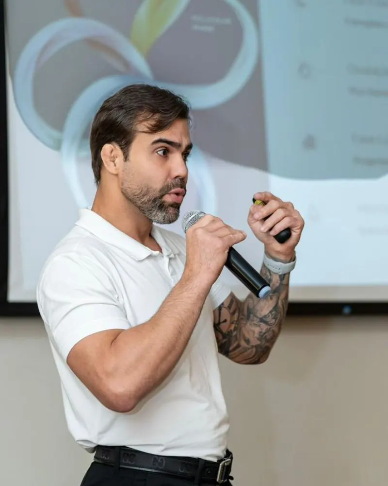 Raphael Rodrigues durante palestra sobre nutrição esportiva, segurando microfone